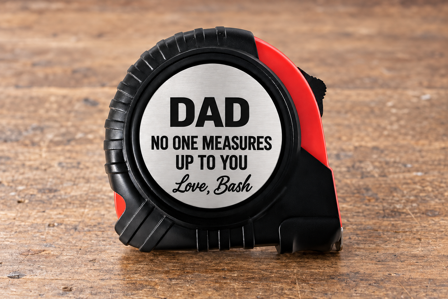 Black and red 25-foot tape measure with a personalized engraved message on its metal face